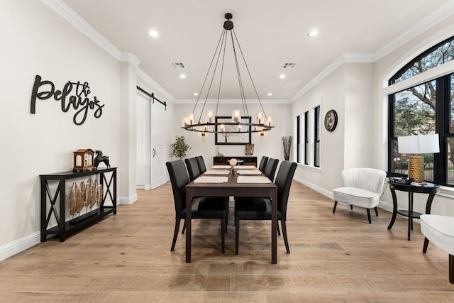 dining room featuring crown molding, a barn door, and light wood-type flooring