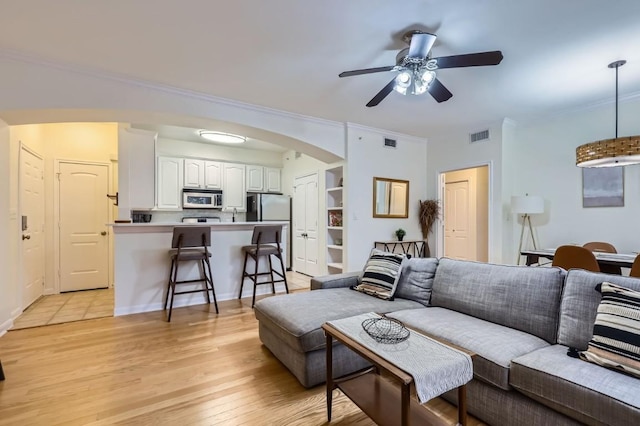 living room featuring crown molding, ceiling fan, and light hardwood / wood-style floors