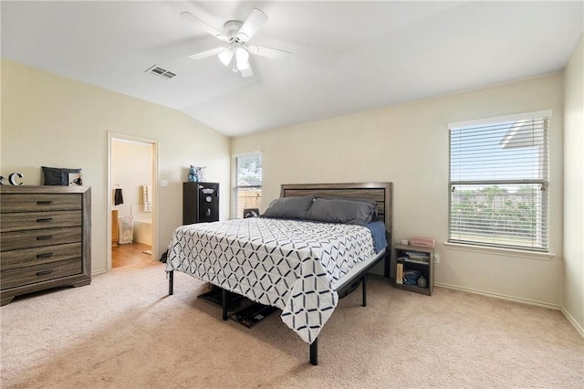 bedroom featuring ceiling fan, ensuite bath, vaulted ceiling, and light carpet