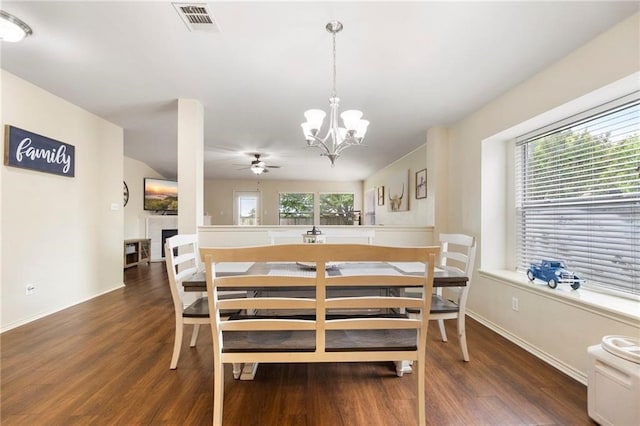 dining room featuring dark wood-type flooring, a fireplace, and ceiling fan with notable chandelier