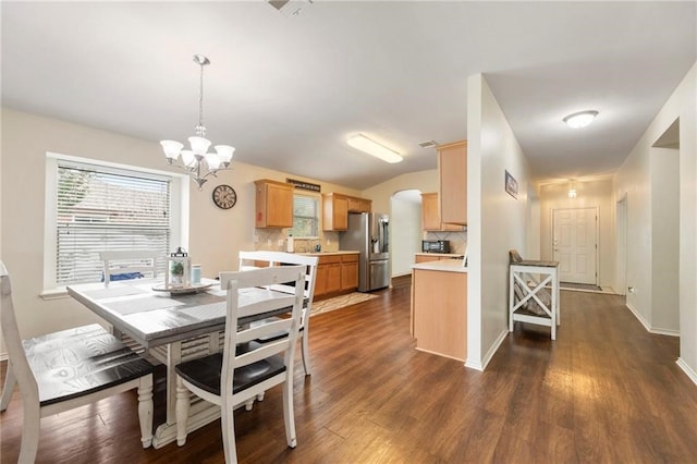 dining space with an inviting chandelier, vaulted ceiling, and dark hardwood / wood-style floors