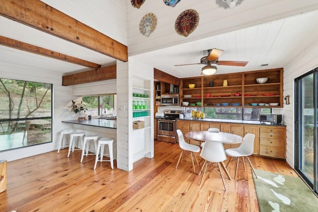 kitchen featuring beamed ceiling, sink, kitchen peninsula, stainless steel appliances, and light wood-type flooring