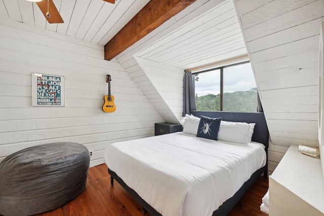 bedroom featuring dark wood-type flooring, wooden walls, and beam ceiling