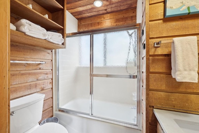 bathroom featuring wooden walls, shower / bath combination with glass door, and toilet