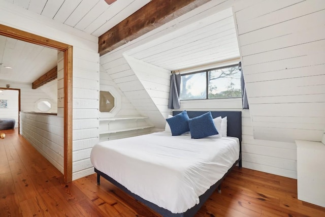 bedroom featuring wood-type flooring, beam ceiling, and wood walls