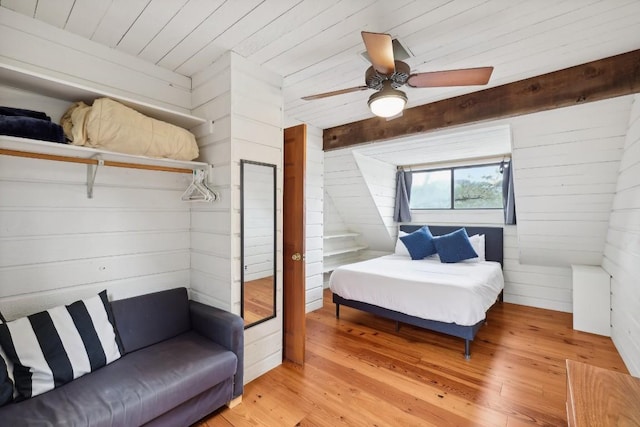 bedroom with ceiling fan, light hardwood / wood-style floors, wooden ceiling, and wood walls