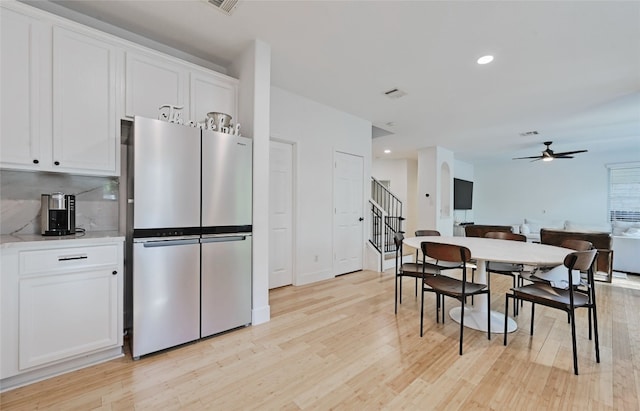 kitchen featuring ceiling fan, white cabinets, stainless steel refrigerator, and light hardwood / wood-style floors