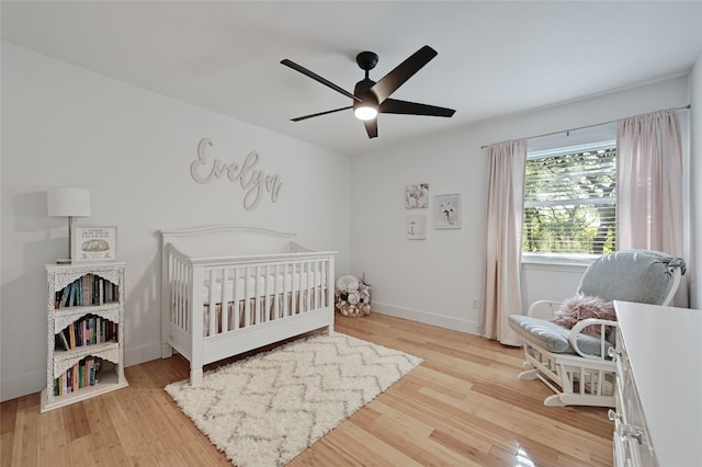 bedroom featuring ceiling fan, a nursery area, and light hardwood / wood-style floors