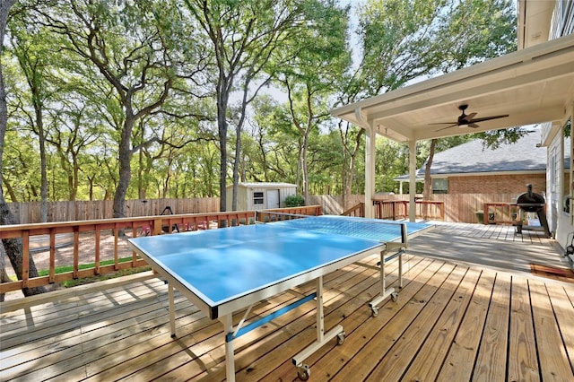 deck featuring ceiling fan, a grill, and a shed