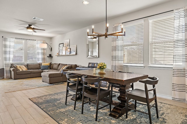 dining space featuring hardwood / wood-style flooring and ceiling fan with notable chandelier