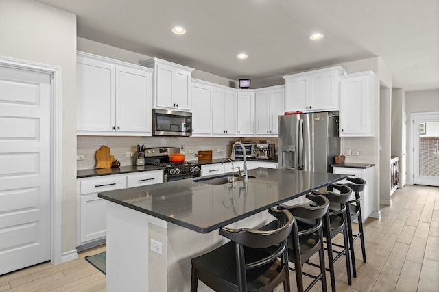 kitchen with sink, stainless steel appliances, an island with sink, and white cabinets