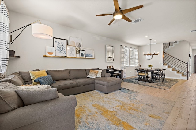 living room with ceiling fan with notable chandelier and wood-type flooring