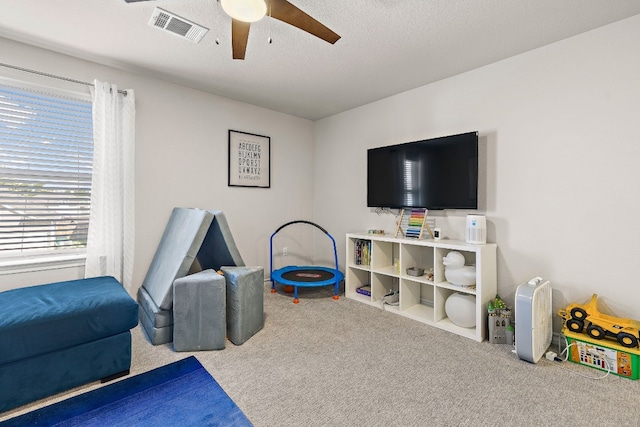 rec room with ceiling fan, carpet, and a textured ceiling