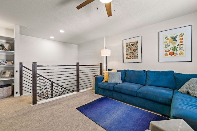 carpeted living room featuring ceiling fan and a textured ceiling