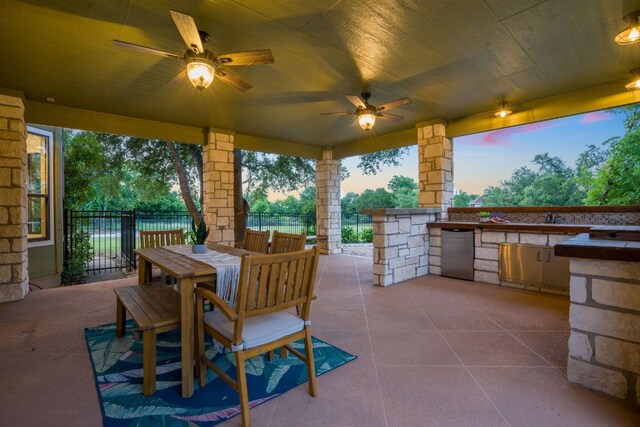 139 Jackrabbit Run, Round Rock, TX 78664 - patio terrace at dusk with an outdoor kitchen, a patio area, a ceiling fan, and outdoor dining space