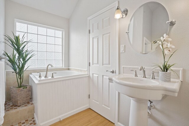 139 Jackrabbit Run, Round Rock, TX 78664 - full bath featuring healthy amount of natural light, a bath, wood finished floors, vaulted ceiling, and a sink