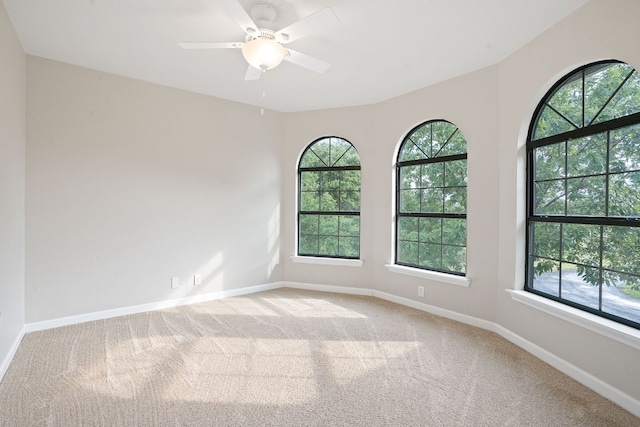 empty room featuring ceiling fan, plenty of natural light, and carpet floors