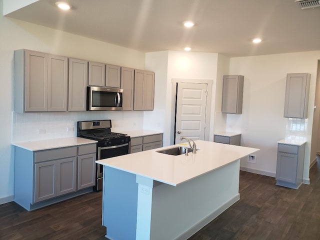 kitchen with gray cabinets, an island with sink, appliances with stainless steel finishes, and sink