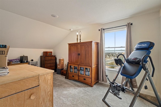 exercise area featuring vaulted ceiling, light colored carpet, and a healthy amount of sunlight