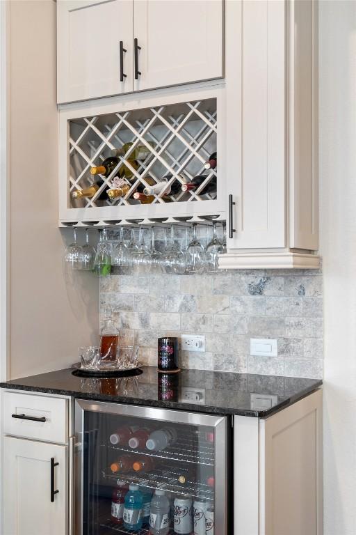 bar featuring tasteful backsplash, white cabinetry, dark stone countertops, and wine cooler