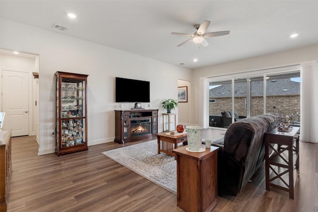 living room with dark wood-type flooring and ceiling fan