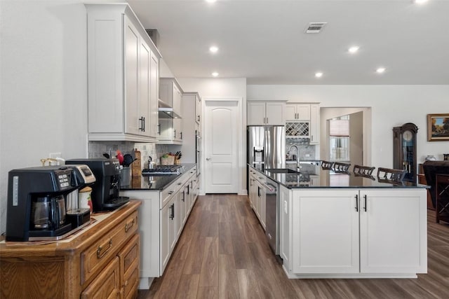 kitchen featuring a kitchen island with sink, sink, stainless steel appliances, and white cabinets