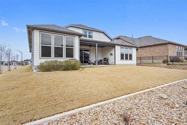 rear view of property featuring ceiling fan and a yard