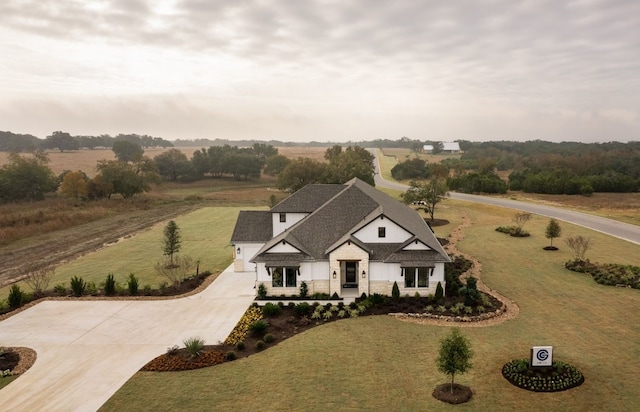 view of front of property with a rural view, driveway, a front lawn, and roof with shingles