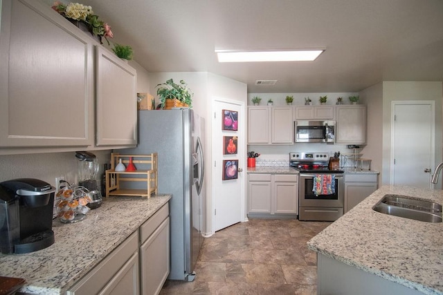 kitchen featuring light stone counters, appliances with stainless steel finishes, and sink