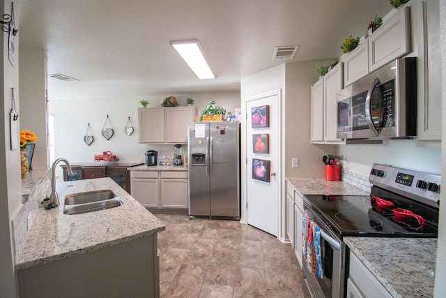 kitchen featuring white cabinetry, appliances with stainless steel finishes, sink, and light stone counters