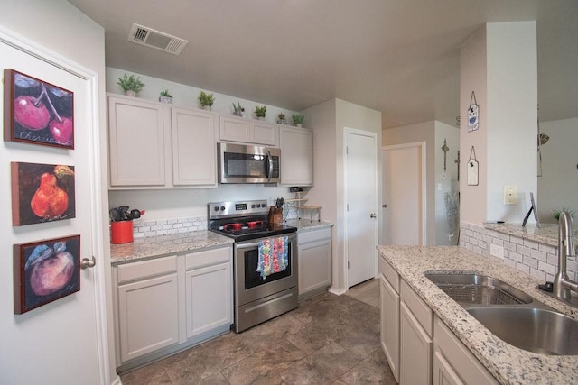 kitchen featuring stainless steel appliances, light stone countertops, sink, and white cabinets