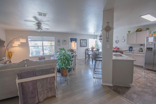 living room featuring ceiling fan, hardwood / wood-style floors, and a textured ceiling