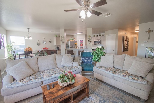 living room featuring ceiling fan with notable chandelier