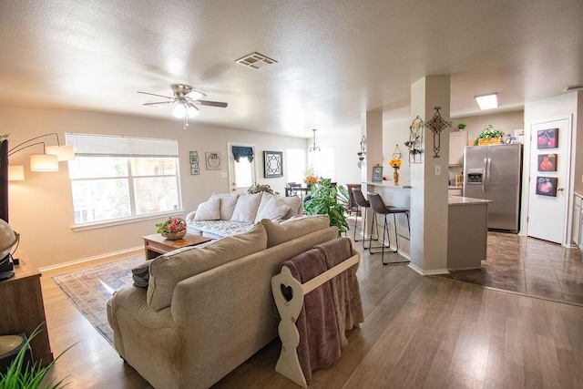 living room with ceiling fan, dark hardwood / wood-style floors, and a textured ceiling