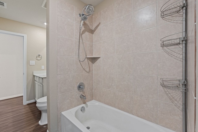 full bathroom with tiled shower / bath, wood-type flooring, vanity, and toilet