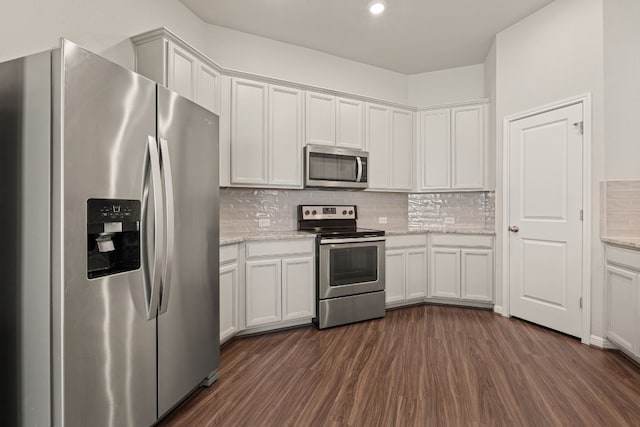 kitchen with stainless steel appliances, dark hardwood / wood-style flooring, light stone countertops, and white cabinets