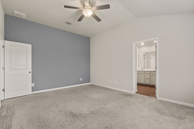 unfurnished bedroom with carpet floors, ensuite bathroom, ceiling fan, and vaulted ceiling