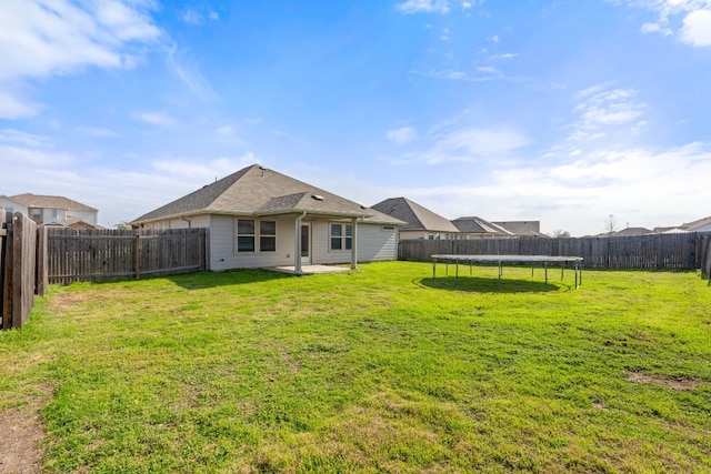 rear view of property with a yard, a patio, and a trampoline