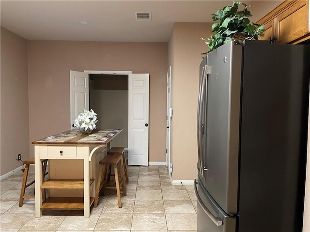 kitchen featuring light tile patterned floors and stainless steel fridge