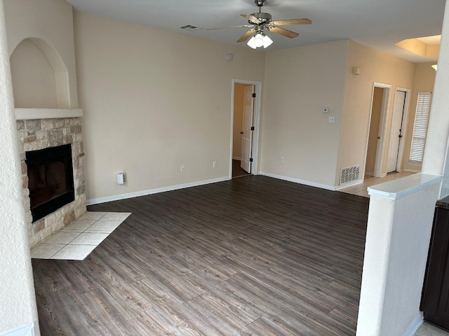 unfurnished living room with ceiling fan, a fireplace, and wood-type flooring