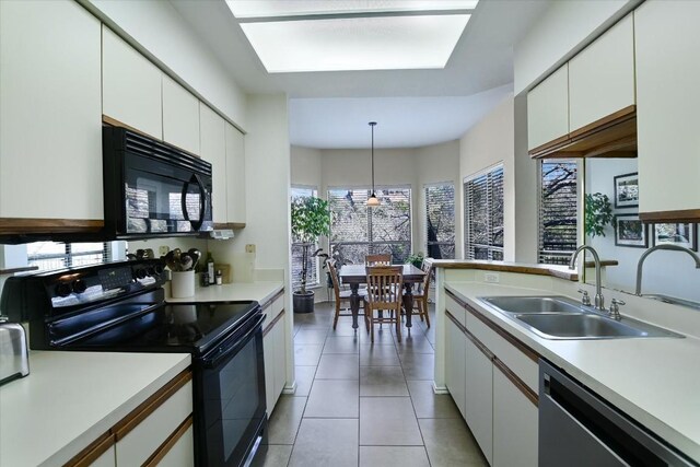 kitchen with sink, black appliances, hanging light fixtures, and white cabinets