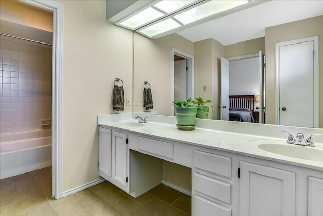 ensuite bathroom with double vanity, tile patterned flooring, a sink, and baseboards