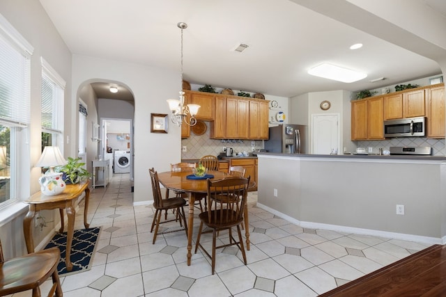 tiled dining room featuring an inviting chandelier and washer / clothes dryer