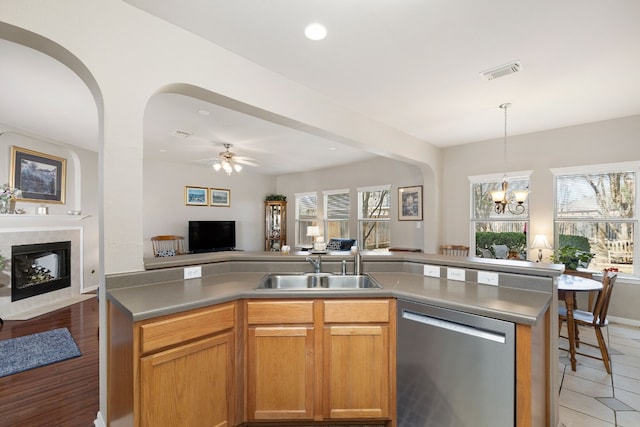 kitchen with sink, decorative light fixtures, stainless steel dishwasher, a kitchen island with sink, and ceiling fan with notable chandelier