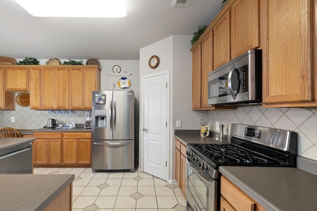 kitchen with light tile patterned floors, backsplash, and appliances with stainless steel finishes