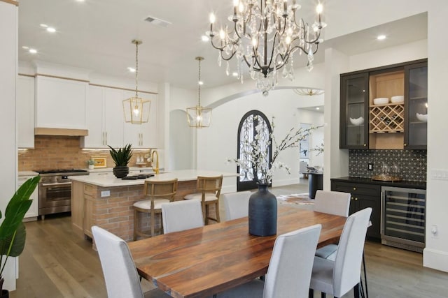 dining area with wet bar, beverage cooler, and light wood-type flooring