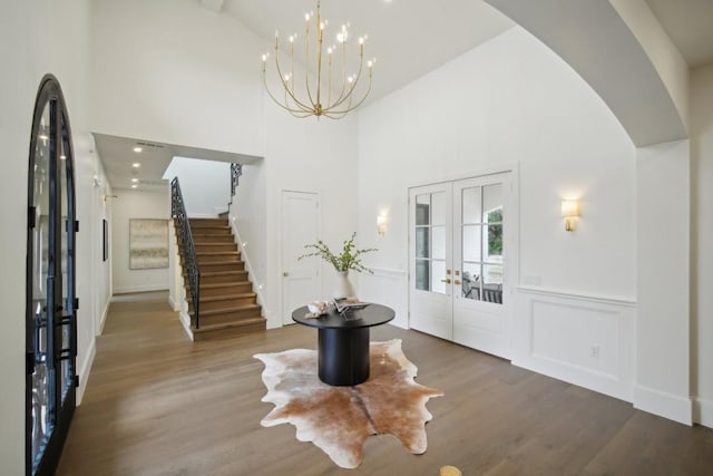 foyer featuring french doors, a towering ceiling, hardwood / wood-style floors, and a notable chandelier