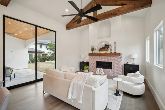 living room featuring hardwood / wood-style floors, a tile fireplace, a wealth of natural light, and beam ceiling