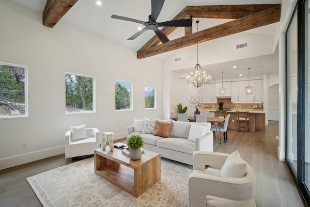 living room featuring hardwood / wood-style flooring, high vaulted ceiling, ceiling fan with notable chandelier, and beam ceiling