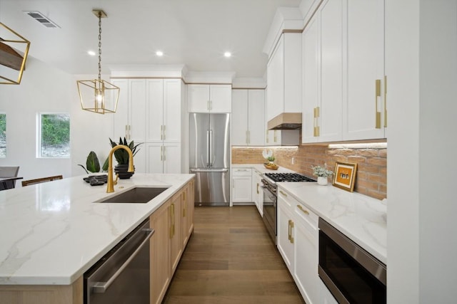 kitchen featuring appliances with stainless steel finishes, white cabinetry, sink, a kitchen island with sink, and light stone counters